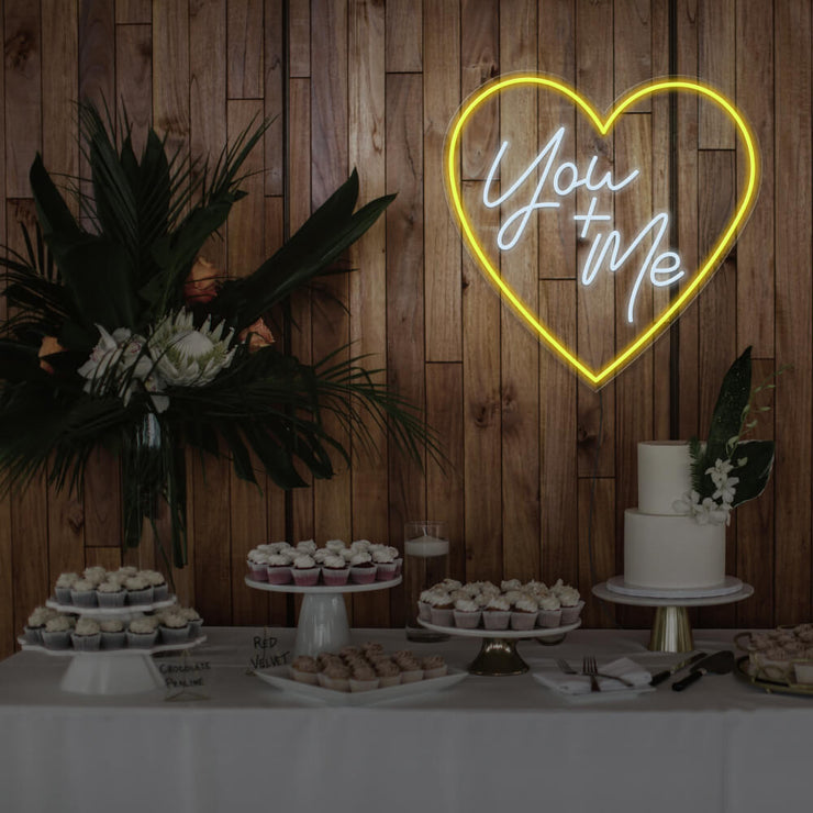 yellow you and me neon sign hanging on timber wall above dessert table