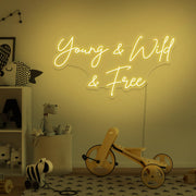 yellow young wild and free neon sign hanging on kids bedroom wall